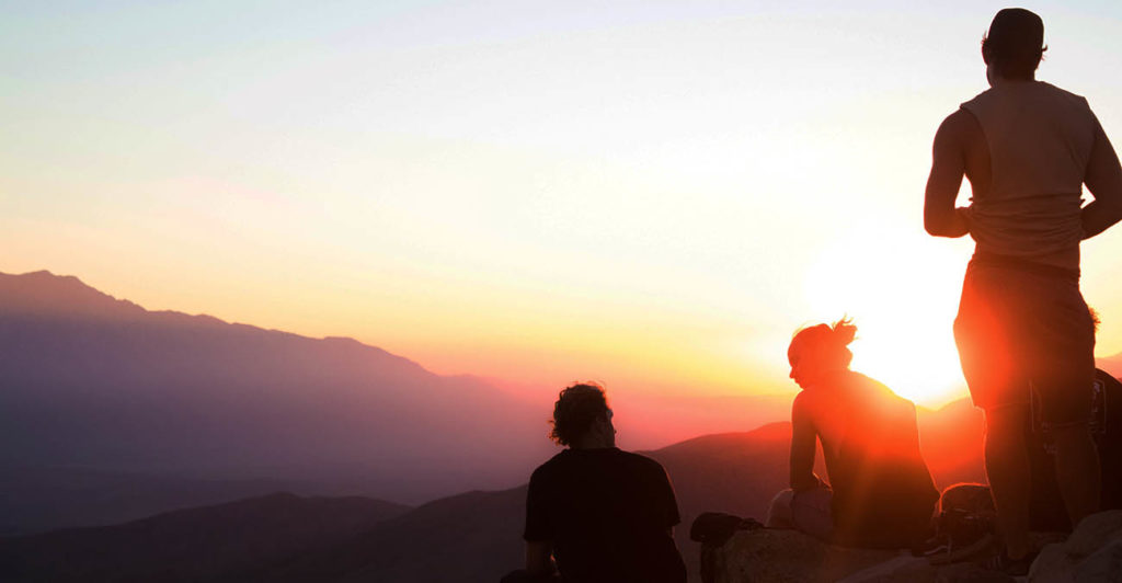 Drei Menschen auf einem Berg bei Sonnenuntergang