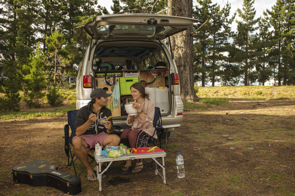 Bild zeigt Daniel und Christina vor ihrem Campervan beim Kochen